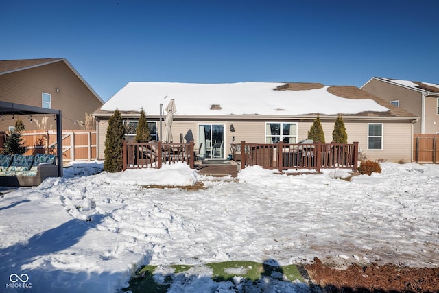 snow covered back of property featuring a deck