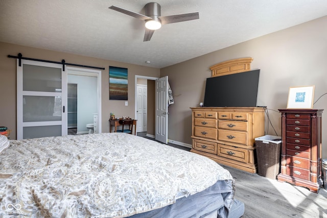 bedroom with ensuite bath, a textured ceiling, ceiling fan, and a barn door