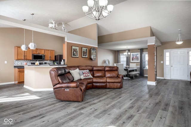 living room featuring a notable chandelier, light wood-type flooring, and vaulted ceiling