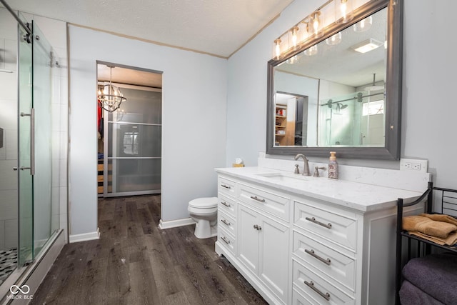 bathroom featuring toilet, a textured ceiling, a shower with shower door, wood-type flooring, and vanity