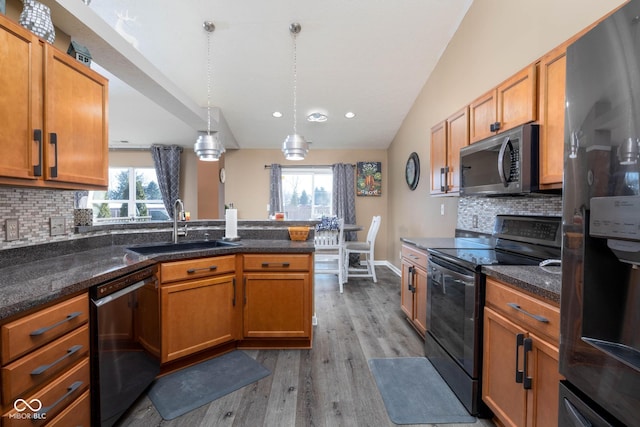 kitchen with dishwashing machine, pendant lighting, stainless steel refrigerator with ice dispenser, range with electric stovetop, and sink