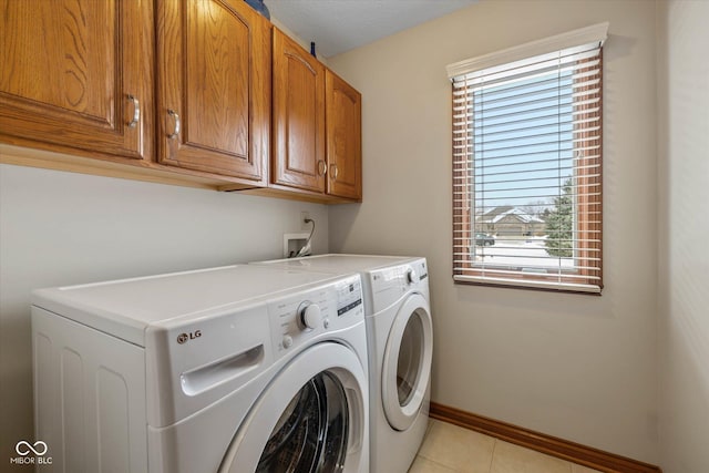 washroom with cabinets, light tile patterned flooring, and washing machine and clothes dryer