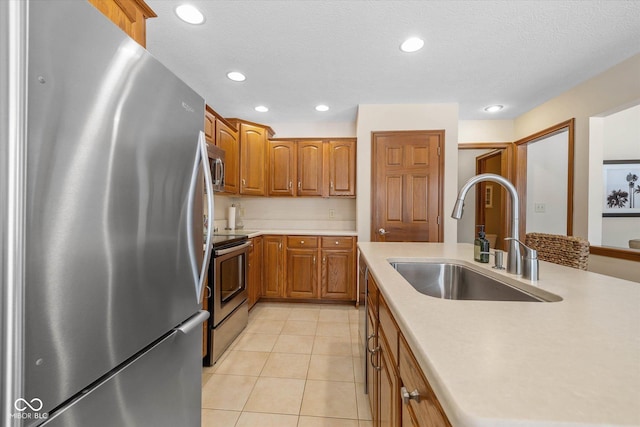 kitchen with light tile patterned floors, sink, a textured ceiling, and appliances with stainless steel finishes