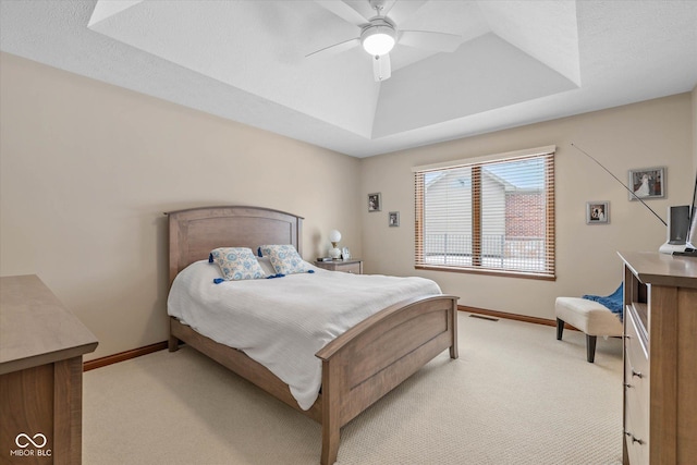 carpeted bedroom with ceiling fan, a tray ceiling, and a textured ceiling