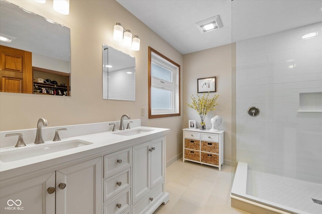 bathroom featuring tile patterned flooring, a tile shower, and vanity