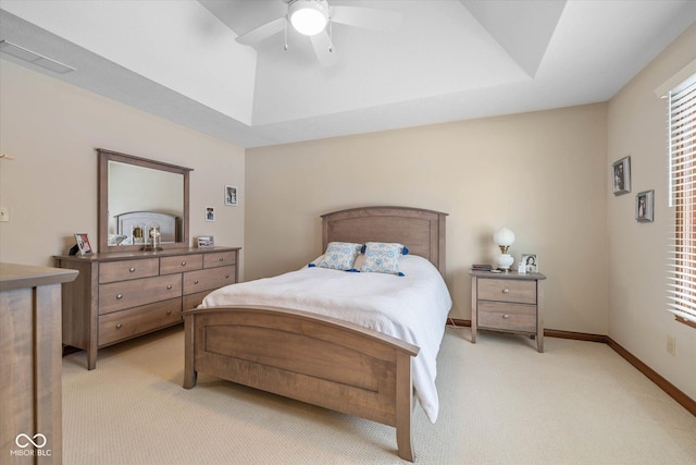 carpeted bedroom featuring ceiling fan and a tray ceiling