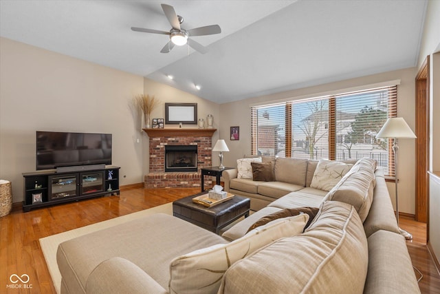 living room with ceiling fan, lofted ceiling, a fireplace, and light hardwood / wood-style flooring