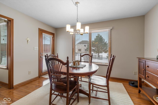 dining space with light hardwood / wood-style floors and a chandelier