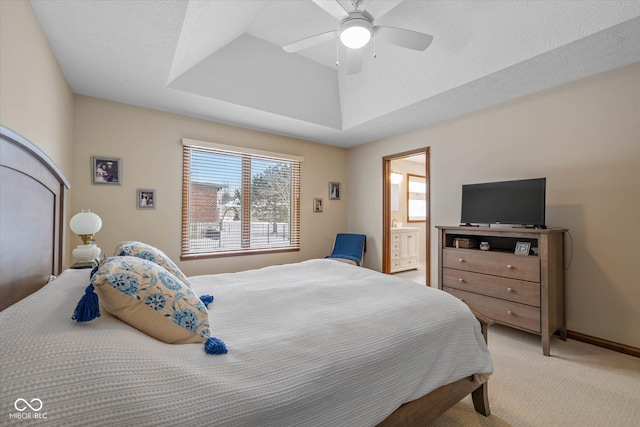 carpeted bedroom featuring a textured ceiling, ceiling fan, a raised ceiling, and ensuite bath