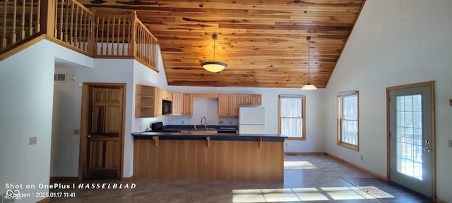 kitchen featuring high vaulted ceiling, white refrigerator, a wealth of natural light, a kitchen bar, and kitchen peninsula