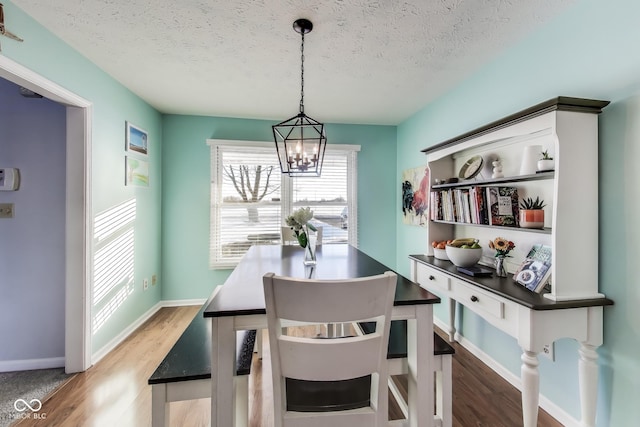 dining room featuring a textured ceiling, an inviting chandelier, and wood-type flooring