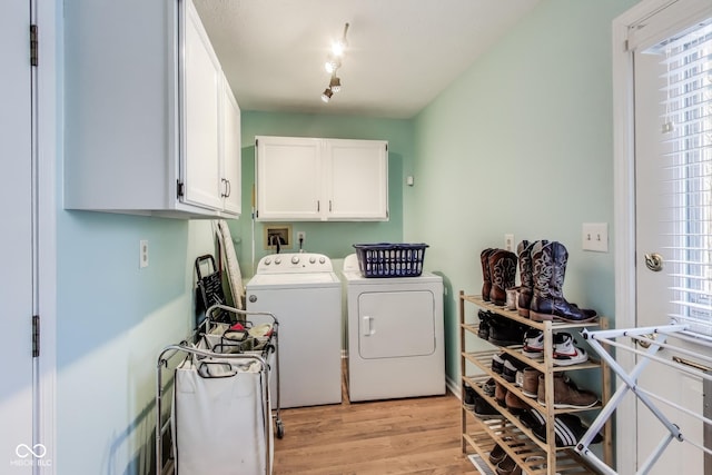 washroom featuring cabinets, light hardwood / wood-style floors, and washer and clothes dryer