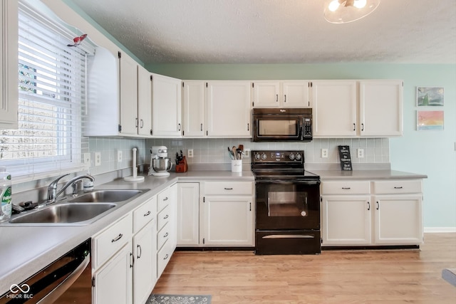 kitchen with backsplash, white cabinets, black appliances, and sink