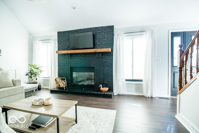 living room with a fireplace, dark wood-type flooring, and plenty of natural light