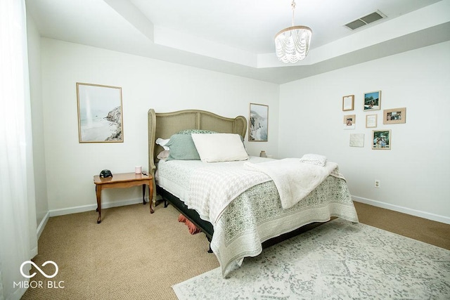 carpeted bedroom featuring a raised ceiling and a notable chandelier