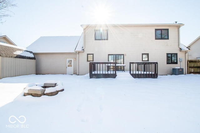 snow covered house with central AC unit and a wooden deck