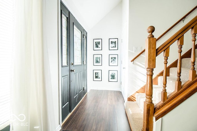 foyer entrance featuring dark wood-type flooring and vaulted ceiling