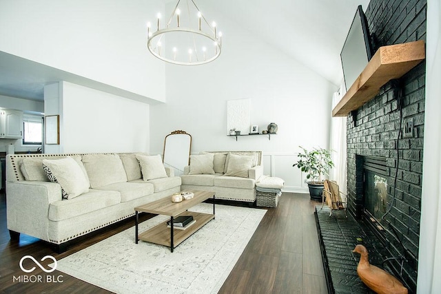 living room featuring a high ceiling, dark wood-type flooring, a notable chandelier, and a fireplace