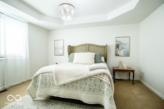 bedroom with an inviting chandelier, a raised ceiling, and light carpet