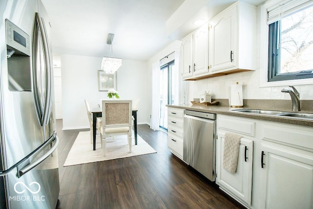 kitchen with sink, stainless steel appliances, pendant lighting, and white cabinetry