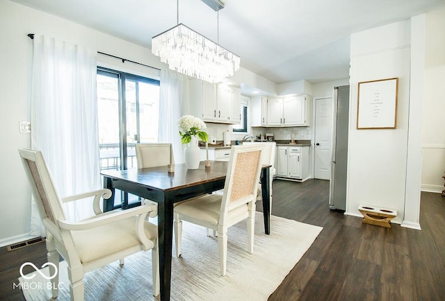 dining area with dark hardwood / wood-style flooring and a chandelier