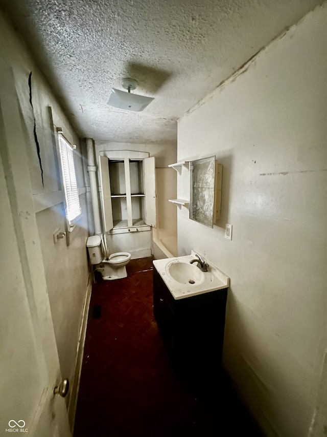 bathroom with a textured ceiling, toilet, and vanity