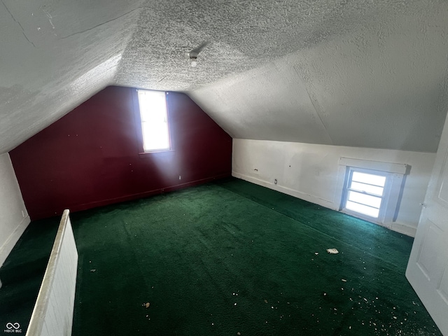 bonus room featuring vaulted ceiling, a textured ceiling, and dark colored carpet