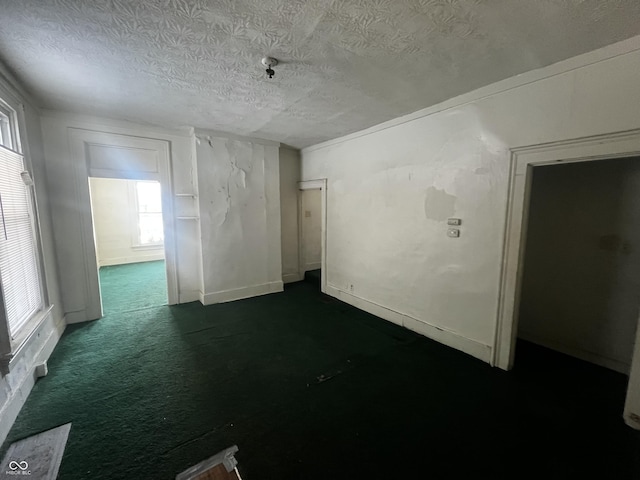 empty room featuring a textured ceiling and dark colored carpet