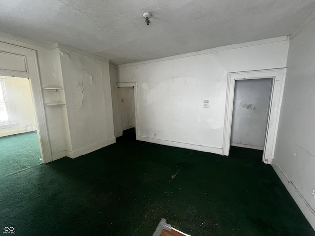 spare room with a textured ceiling and dark colored carpet