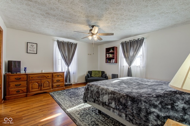 bedroom with ceiling fan, a textured ceiling, hardwood / wood-style flooring, and radiator