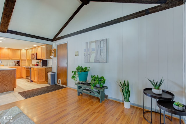 living room featuring vaulted ceiling with beams and light hardwood / wood-style floors