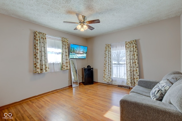 living room featuring ceiling fan, a textured ceiling, and hardwood / wood-style flooring