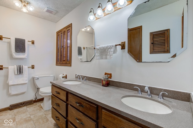 bathroom featuring a textured ceiling, toilet, and vanity