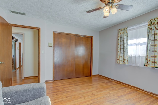 bedroom featuring ceiling fan, a closet, light wood-type flooring, and a textured ceiling