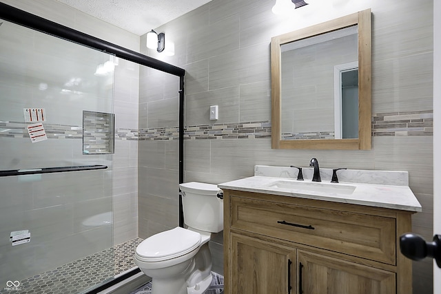 bathroom featuring vanity, toilet, a shower with shower door, and tile walls