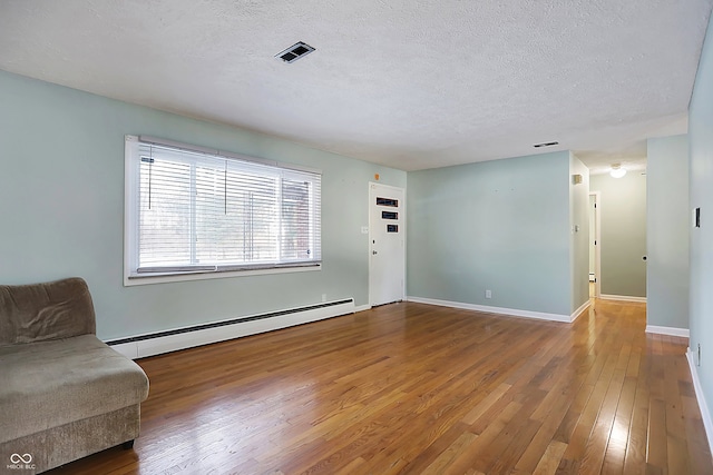 living room with hardwood / wood-style floors, a textured ceiling, and a baseboard heating unit