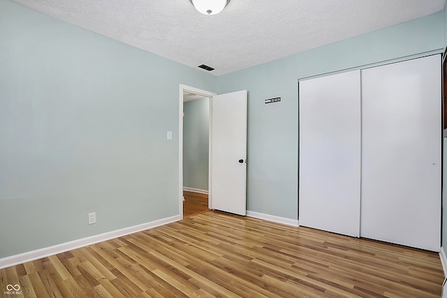 unfurnished bedroom featuring a closet, light hardwood / wood-style floors, and a textured ceiling