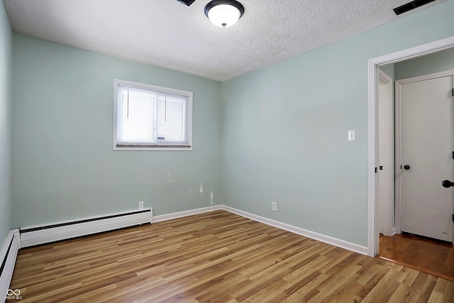 unfurnished room with a baseboard heating unit, light hardwood / wood-style floors, and a textured ceiling