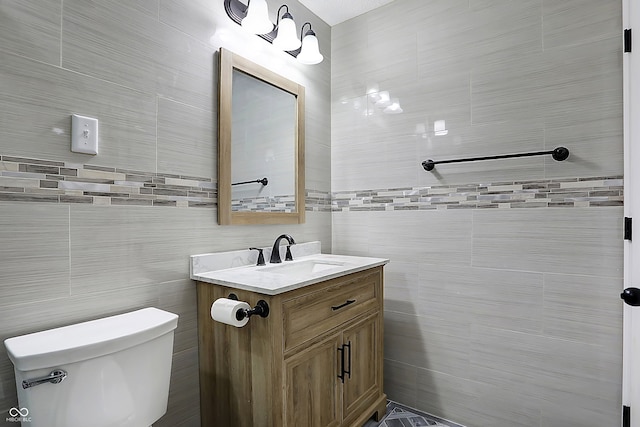 bathroom with vanity, toilet, and tile walls