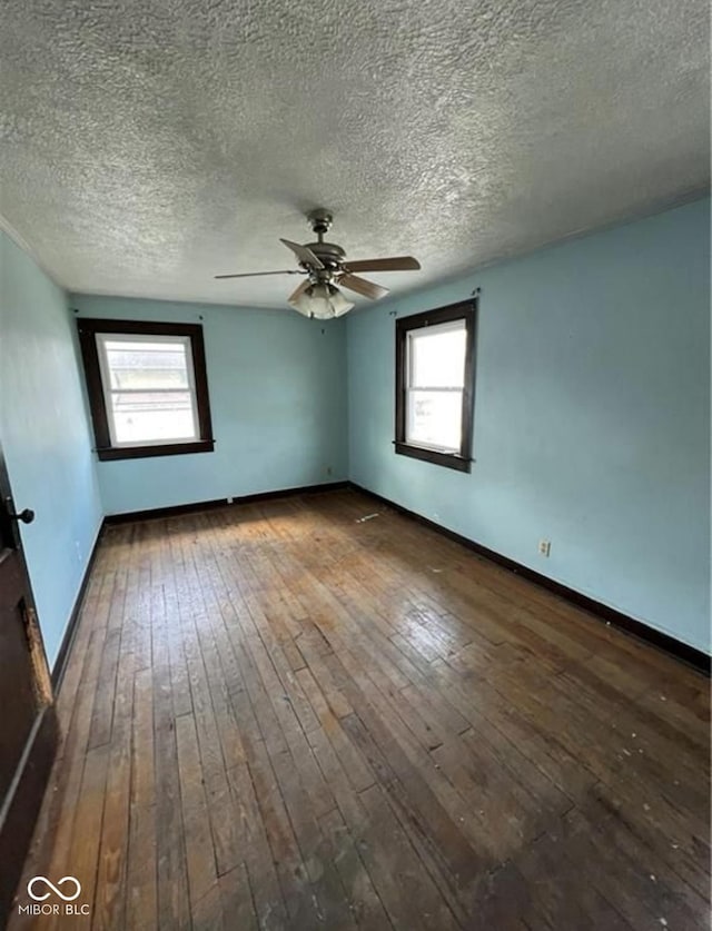 empty room with ceiling fan, a textured ceiling, and dark hardwood / wood-style floors