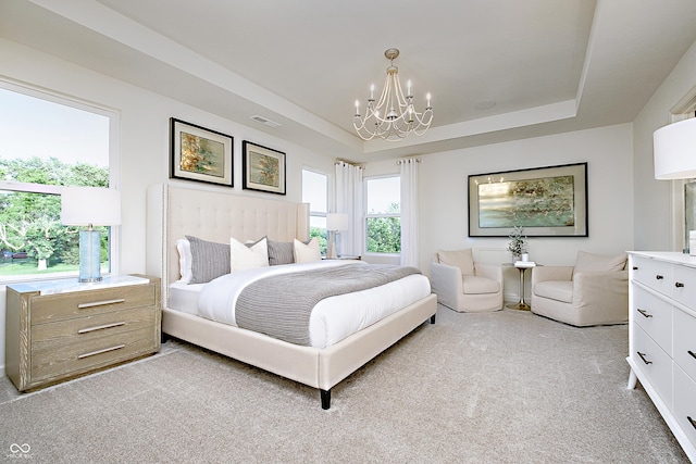 bedroom featuring an inviting chandelier, light colored carpet, and a tray ceiling