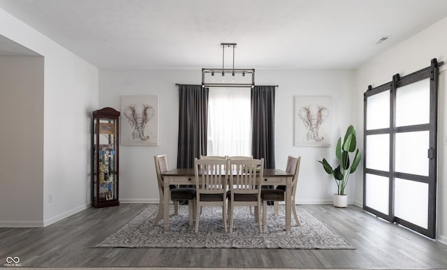 dining space with a barn door, plenty of natural light, and dark hardwood / wood-style flooring