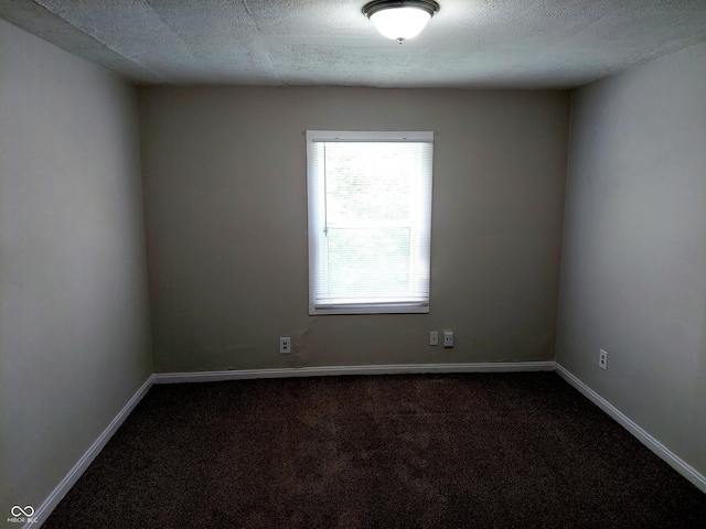 unfurnished room with a textured ceiling and dark carpet