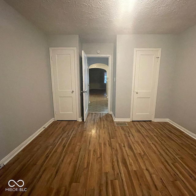 spare room featuring a textured ceiling and dark wood-type flooring