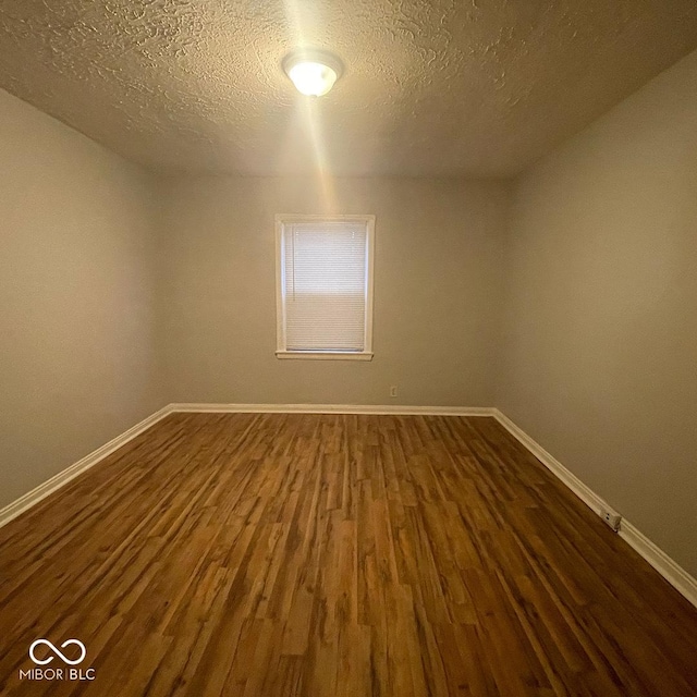 empty room featuring a textured ceiling and dark hardwood / wood-style floors