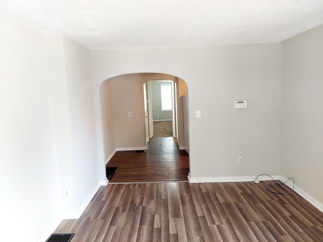 empty room featuring a textured ceiling and dark hardwood / wood-style flooring