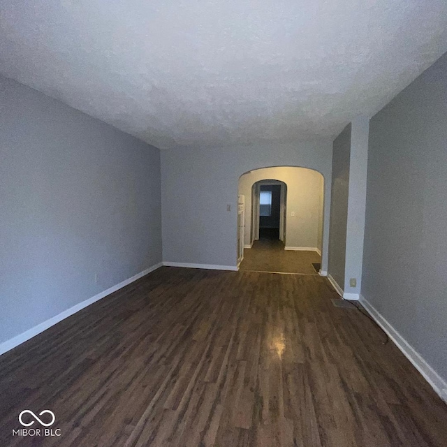 spare room with a textured ceiling and dark hardwood / wood-style floors