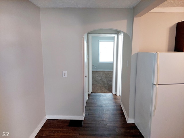 hall with a textured ceiling and dark hardwood / wood-style floors