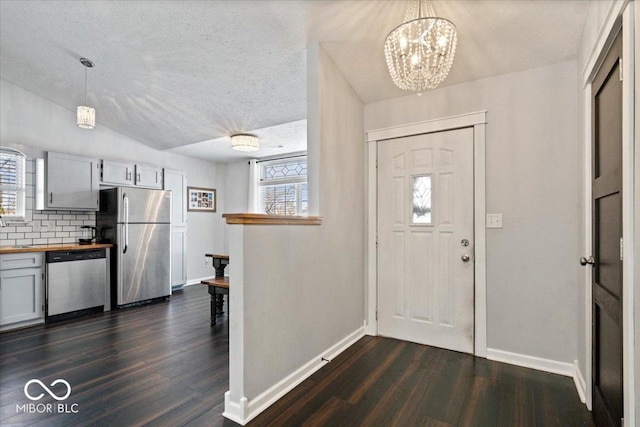 entryway with a textured ceiling, dark hardwood / wood-style flooring, and an inviting chandelier