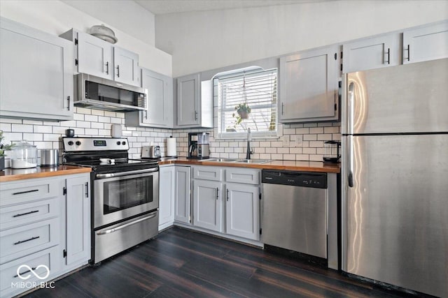 kitchen with white cabinetry, wooden counters, stainless steel appliances, dark hardwood / wood-style floors, and sink